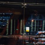 Piso de negociação de bolsa de valores com monitores exibindo cotações e movimento de investidores