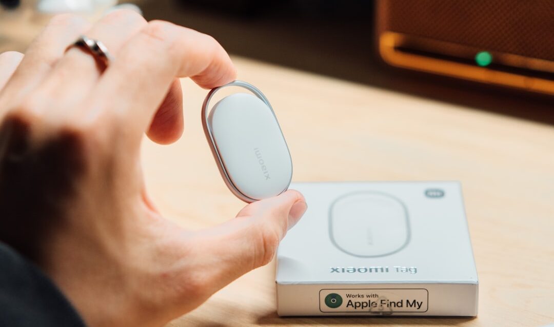 Rastreador inteligente ao lado de smartphone com tela de localização, fundo neutro e iluminação suave.