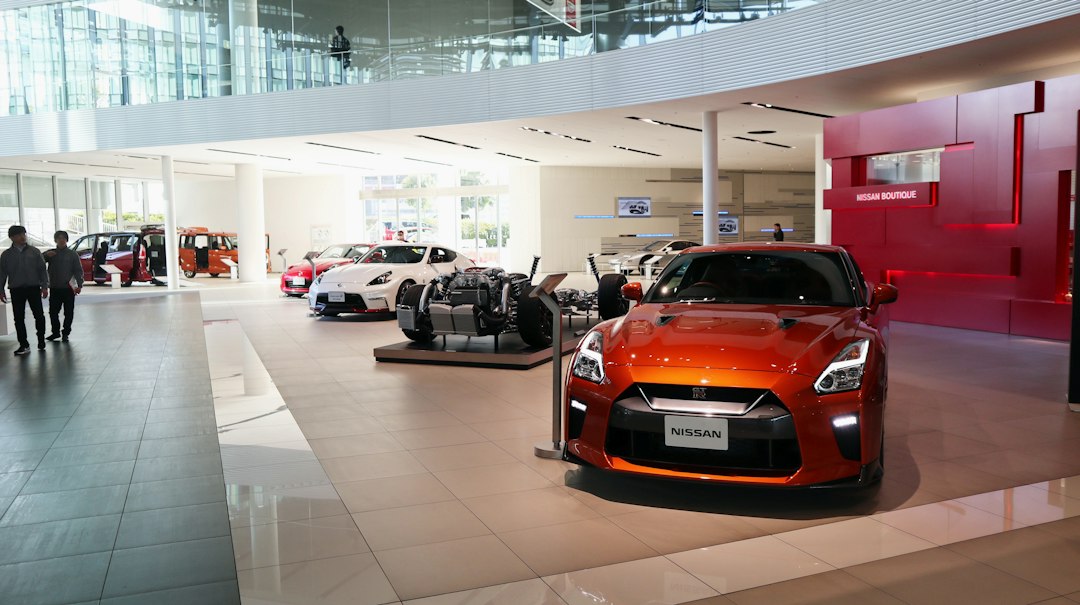 jac-motors-vendas-online-brasil Showroom de concessionária com carro elétrico compacto e picape em exposição, piso polido e iluminação direcionada.
