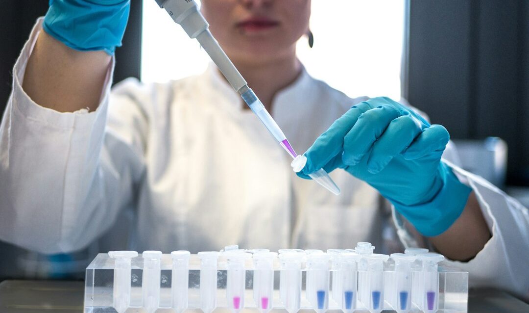 Cientista usando pipeta com tubos de ensaio no laboratório.