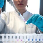 Cientista usando pipeta com tubos de ensaio no laboratório.